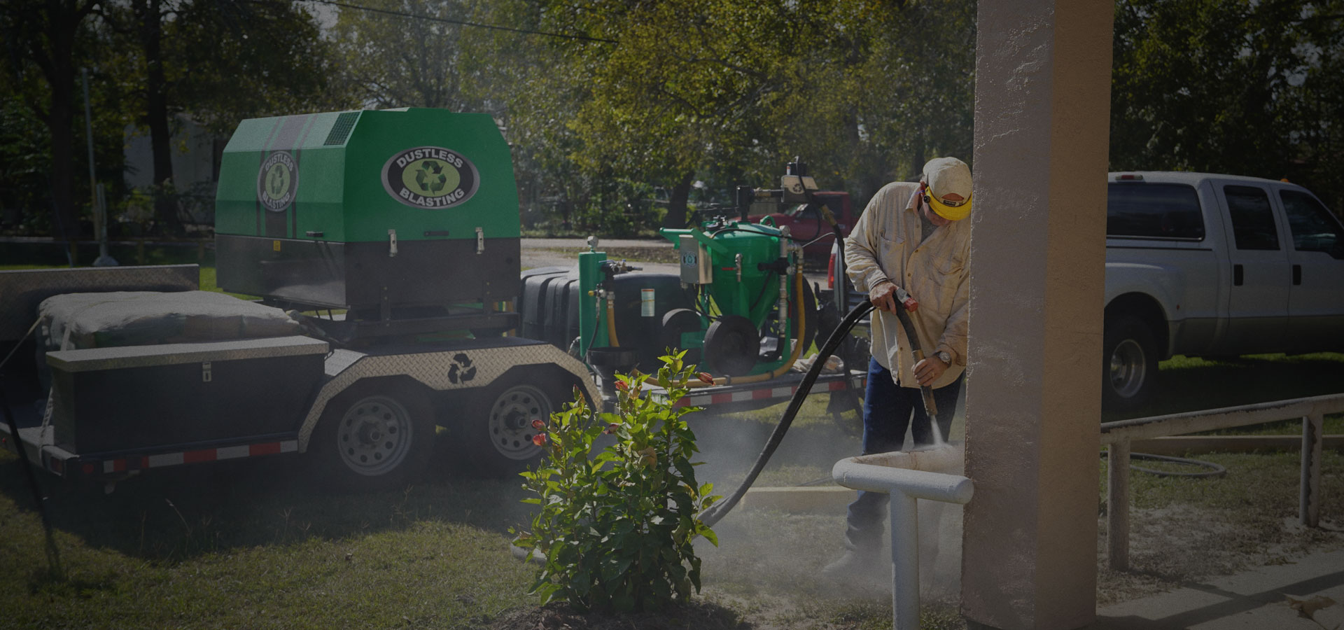 An ALLPRO BLASTERS technician dustless blasting on site next to the mobile Dustless Blasting rig